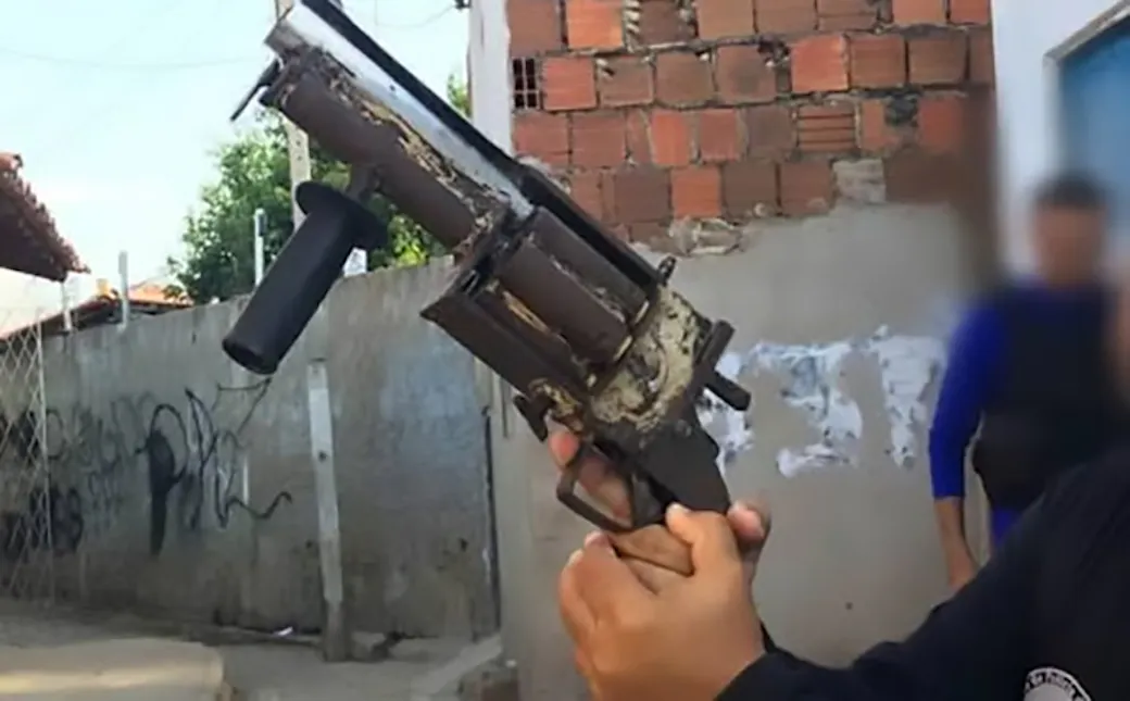 Crude handmade multi-barrel firearm with a vertical foregrip held up by a police officer in Brazil