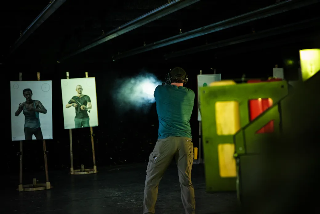 Shooter firing a handgun at an indoor range