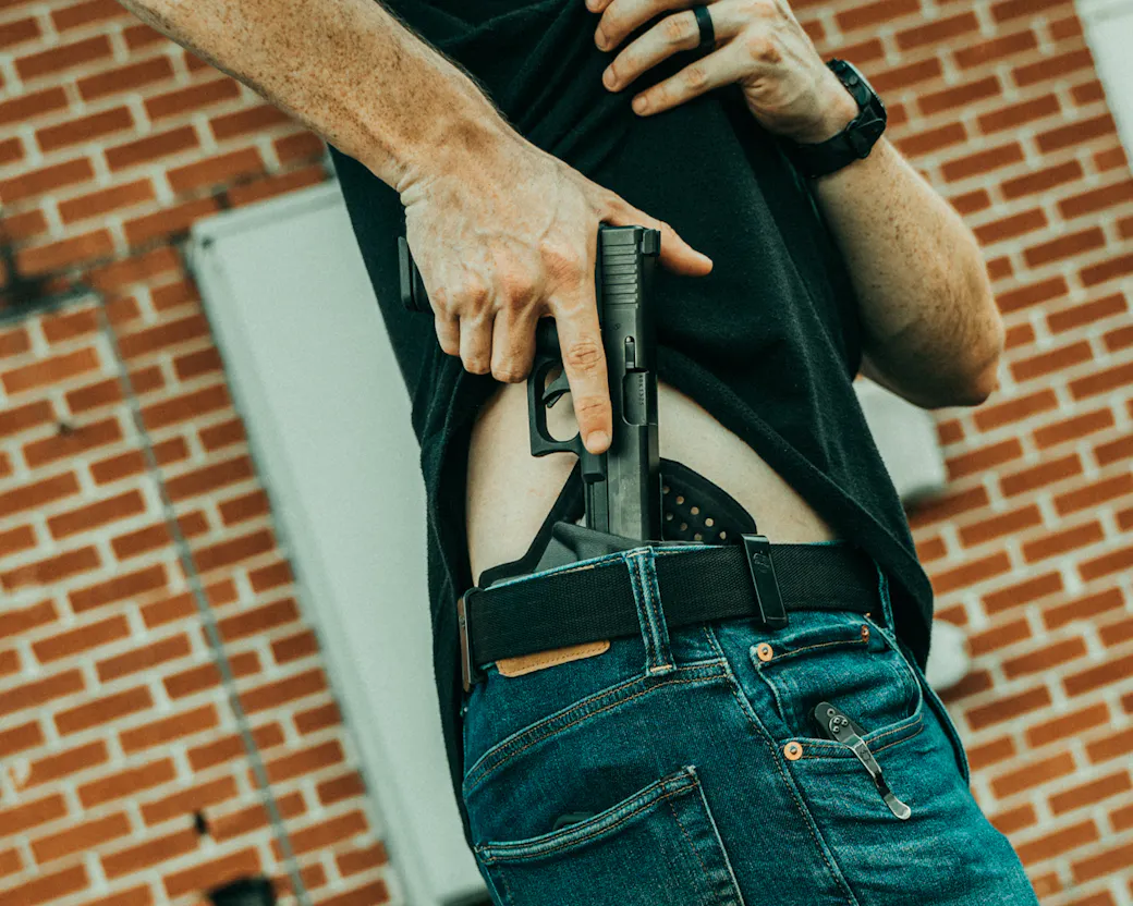 Person drawing an IWB holster while wearing it concealed