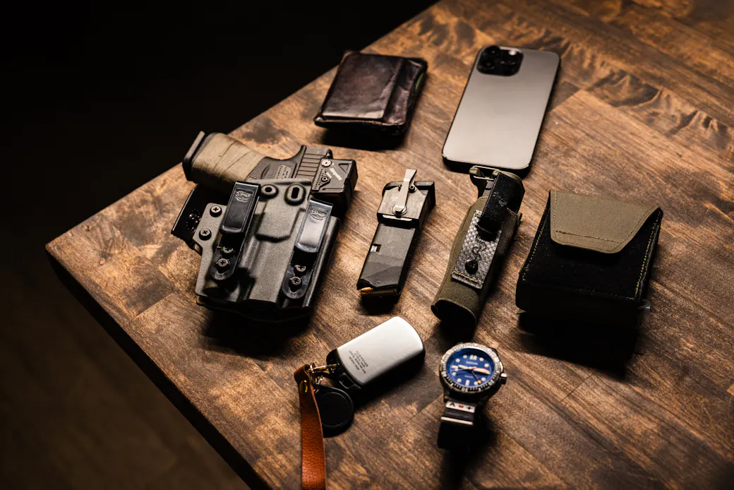 Holstered carry gun on a table next to everyday carry items