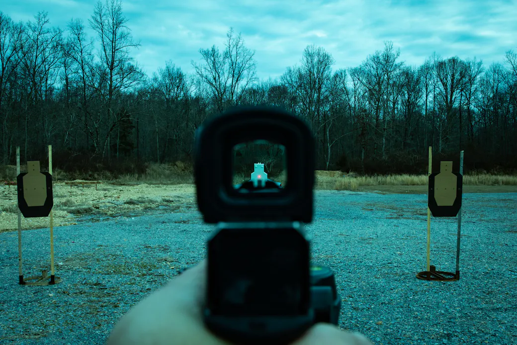View through a pistol optic showing the red dot superimposed on a target downrange
